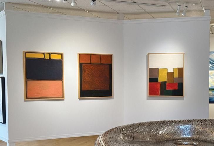 Tre färgstarka abstrakta målningar belysta i ett galleri